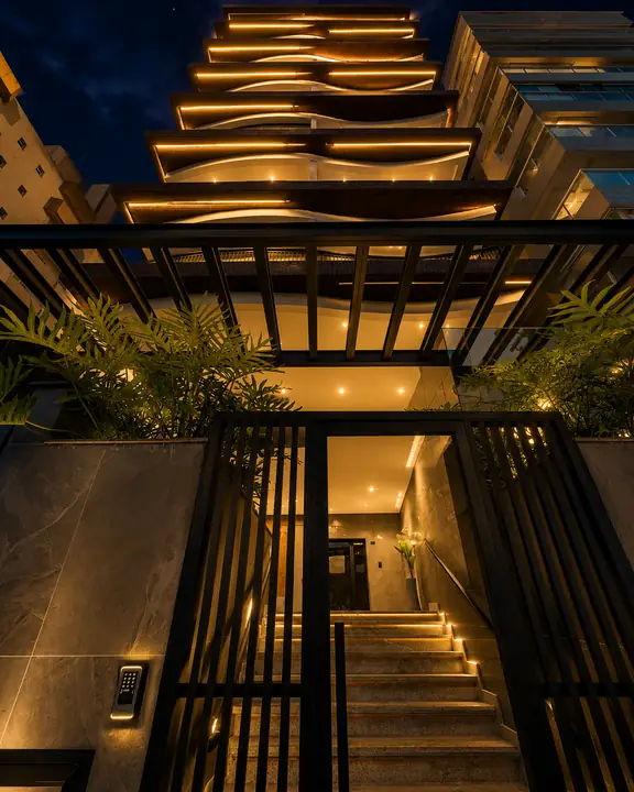 Entrada social do Residence Evoque iluminada à noite