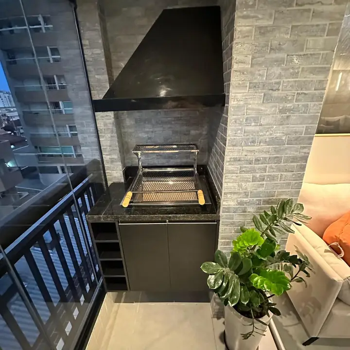Varanda gourmet com churrasqueira a carvão no apartamento decorado